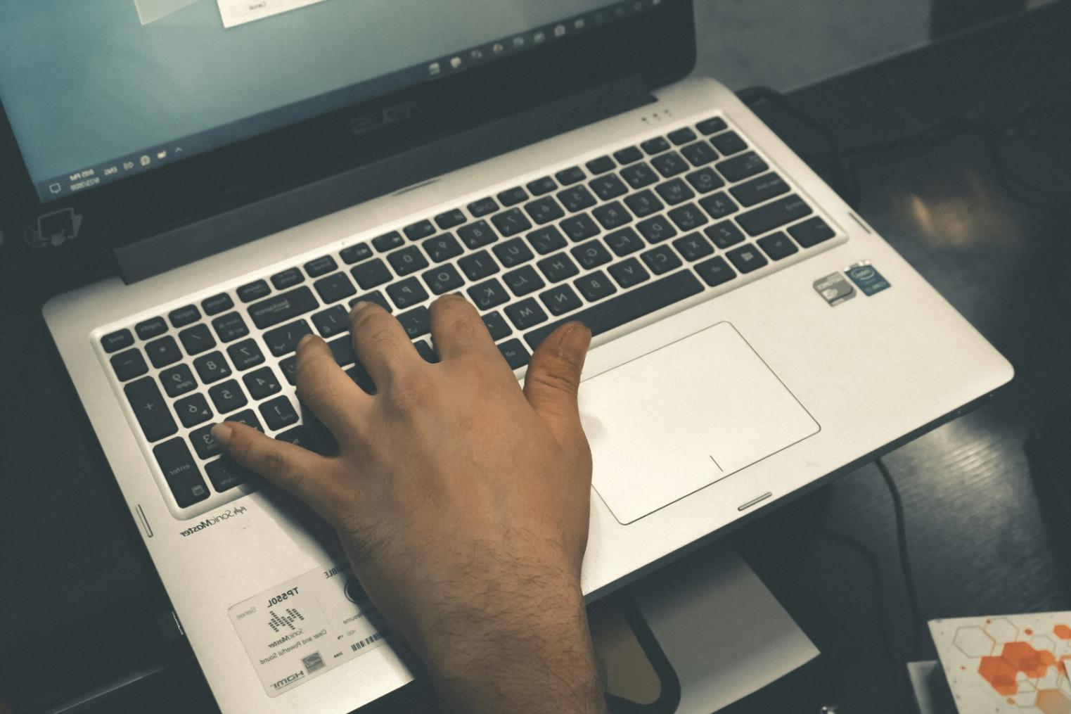 Person arbeitet konzentriert am Laptop mit Finanzunterlagen